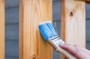 a blue paint brush against a wooden plank